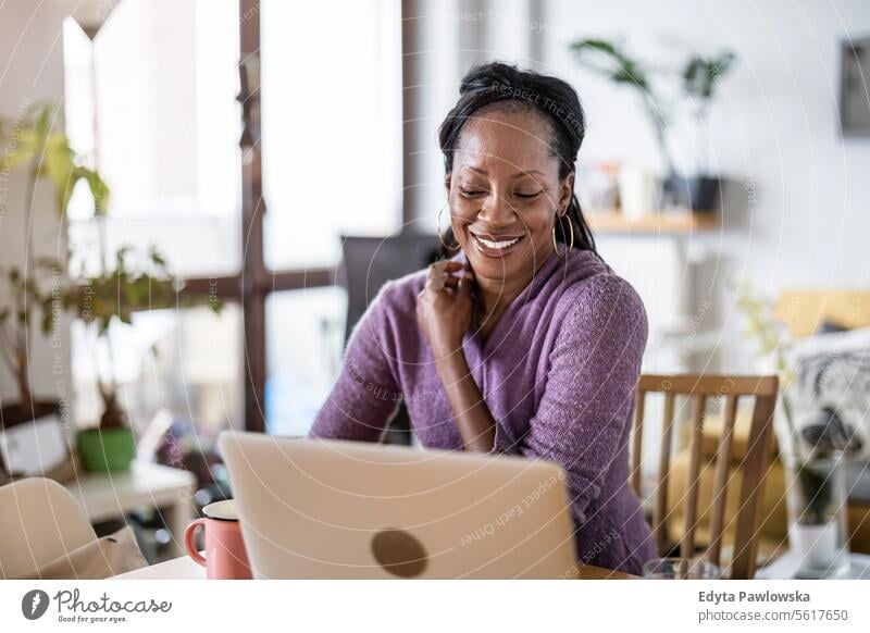 Smiling woman working on laptop at home people joy black natural attractive black woman happiness happy real people mature adult daily life adults one person