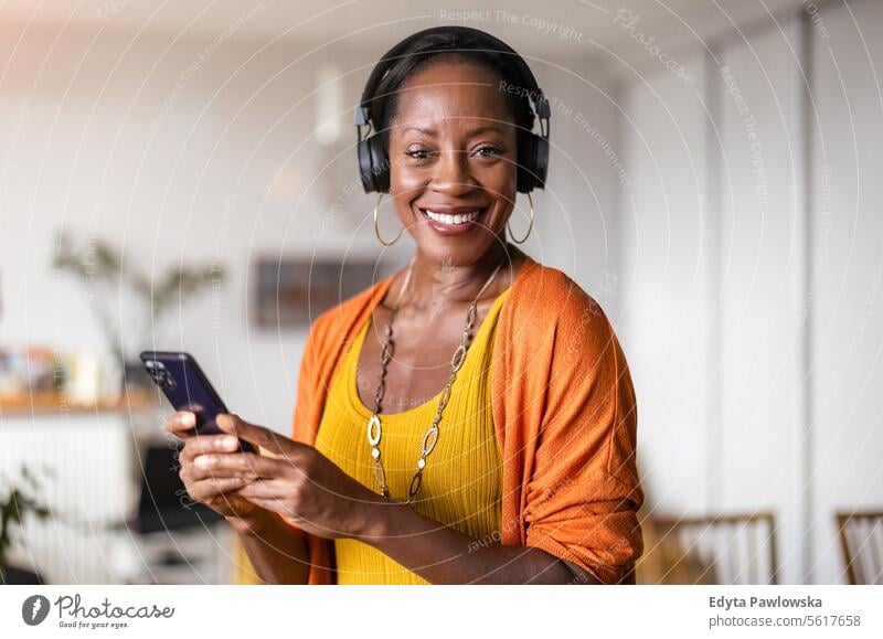 Woman listening to music with headphones in the living room at home people joy woman black natural attractive black woman happiness happy real people mature