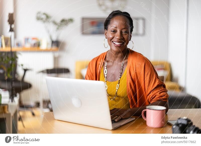 Smiling woman working on her laptop at home people Joy Woman Black naturally Attractive black woman Happiness Happy real people Mature more adult Everyday life