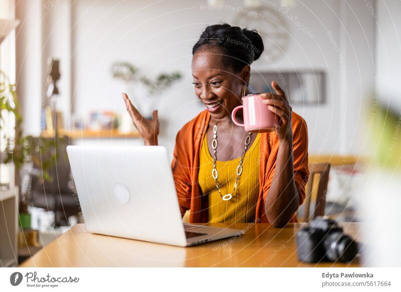 Smiling woman working on laptop at home people joy black natural attractive black woman happiness happy real people mature adult daily life adults one person