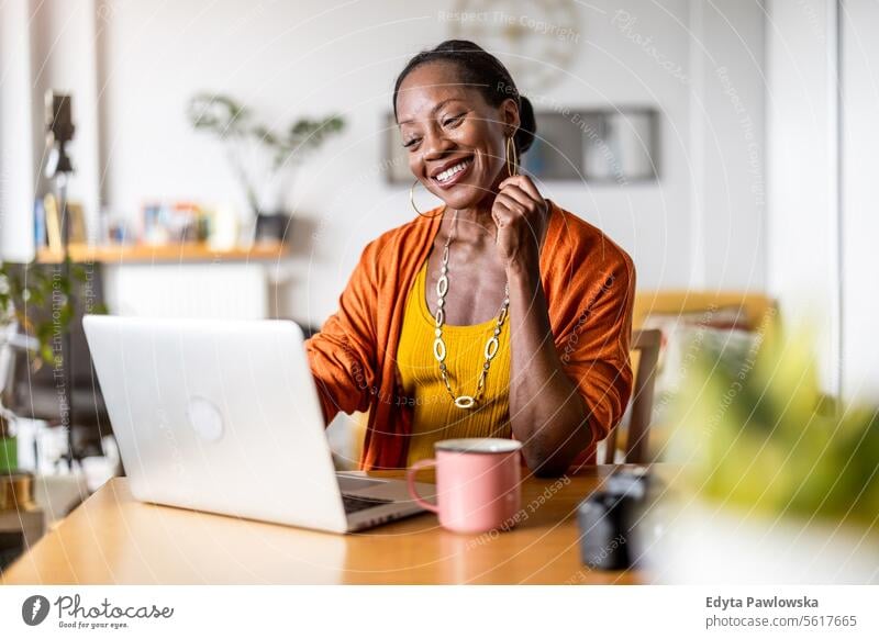 Smiling woman working on laptop at home people joy black natural attractive black woman happiness happy real people mature adult daily life adults one person