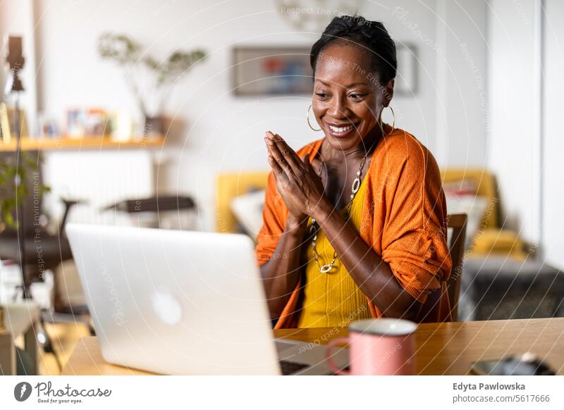 Smiling woman working on laptop at home people joy black natural attractive black woman happiness happy real people mature adult daily life adults one person