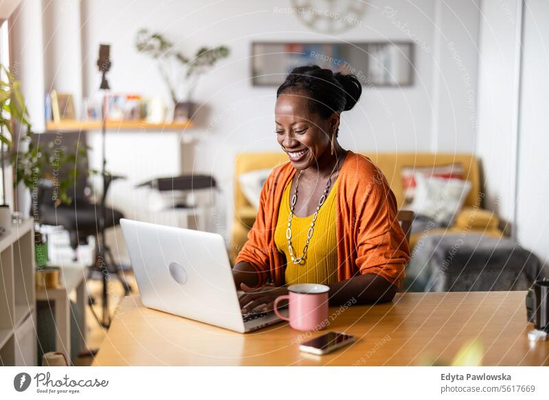 Smiling woman working on laptop at home people joy black natural attractive black woman happiness happy real people mature adult daily life adults one person