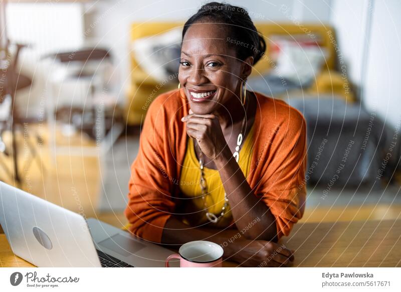 Smiling woman working on laptop at home people joy black natural attractive black woman happiness happy real people mature adult daily life adults one person