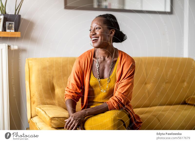 Portrait of smiling woman relaxing on sofa at home people joy black natural attractive black woman happiness happy real people mature adult daily life adults