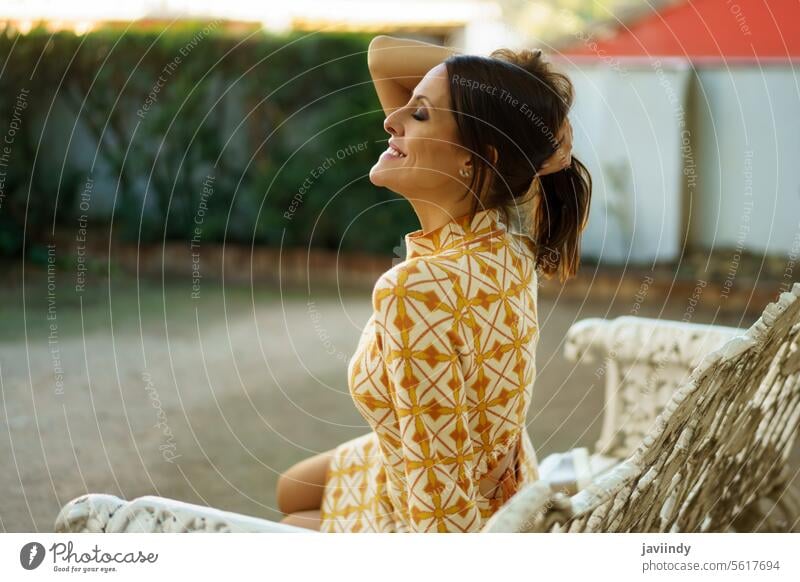 Dreamy cheerful woman resting while enjoying fresh air outdoors bench thoughtful relax dreamy happy smile nature harmony lifestyle carefree positive glad