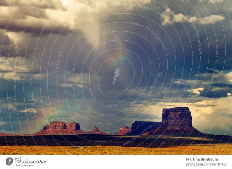 Dark sky and a rainbow over monument valley dark skies weather landscape travel desert nature rock red tourism arizona western stone navajo america summer