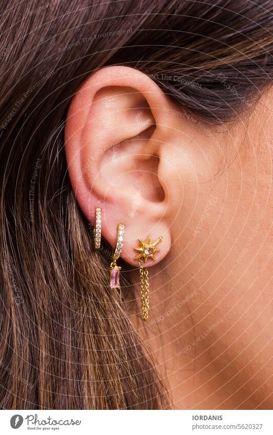 Woman ear with mulriple piercings wearing beautiful earrings with zirconia accessories accessory attractive beauty close-up closeup design detail elegance