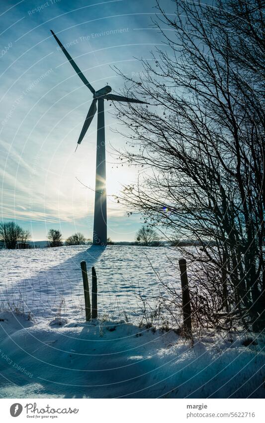 Wind turbine in winter Pinwheel Wind energy plant Renewable energy wind power Winter Snow Sun Energy industry Sunlight Sunbeam Clouds Sky Fence Fence post