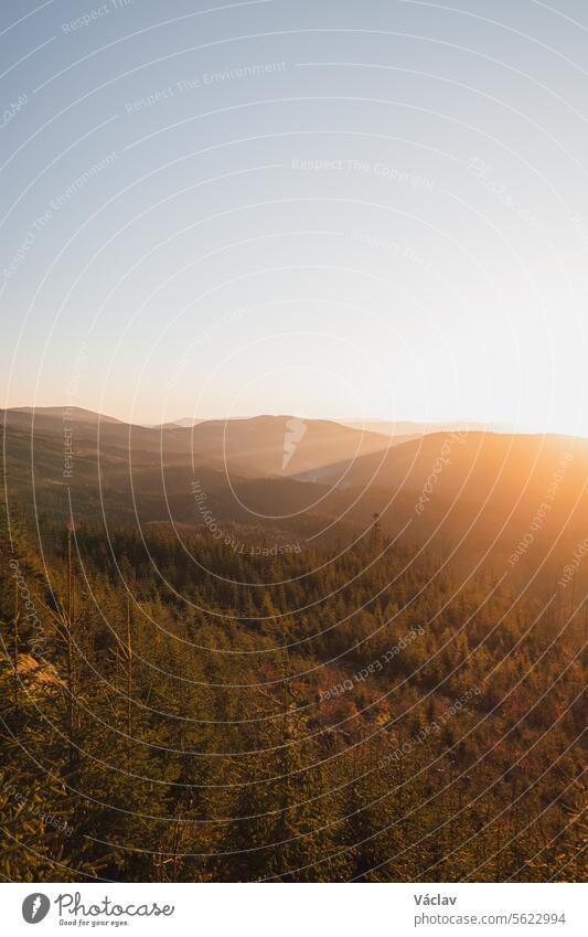 Sun rises from behind the mountain and the sun's rays gradually illuminate the valley in Beskydy mountains, Czech Republic sunset outside colourful sunshine