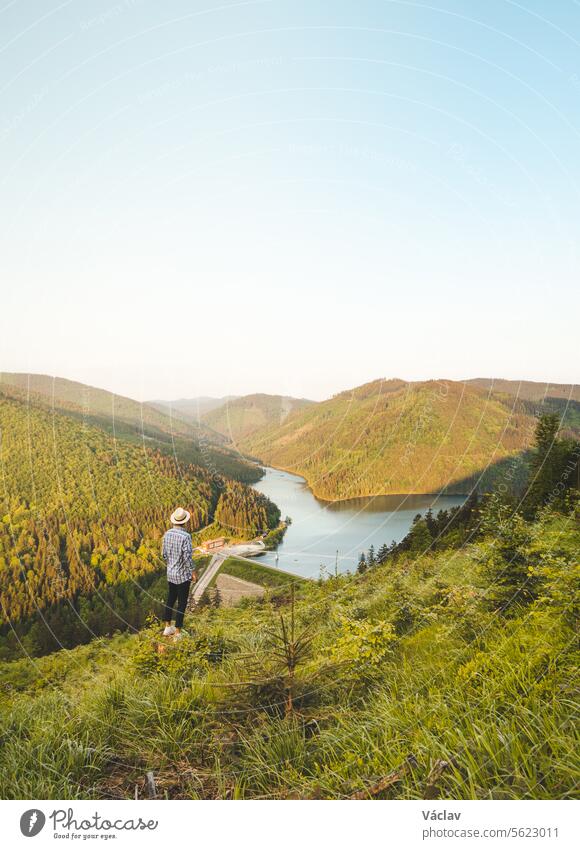 Man in shirt and hat watching the sunset illuminating the Sance Dam, Ostravice, Beskydy Mountains, Czech Republic. Enchanting nature in Central Europe Sunbeam