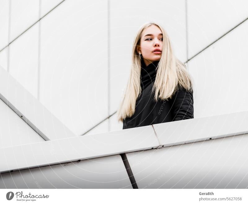 young girl with blond hair and black clothes against a gray building adult architecture autumn beautiful beauty blonde city dreamy erase face fashion female