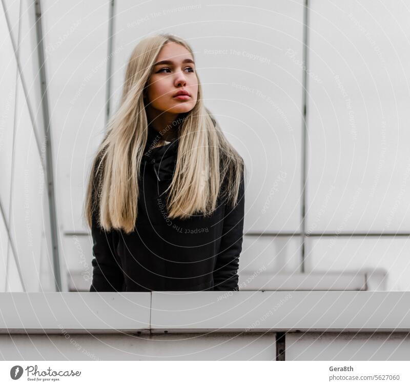 young girl with blond hair and black clothes against a gray building adult architecture autumn beautiful beauty blonde city dreamy erase face fashion female