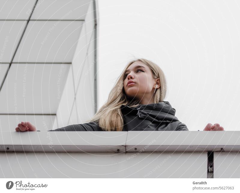 young girl with blond hair and black clothes against a gray building adult architecture autumn beautiful beauty blonde city dreamy erase face fashion female