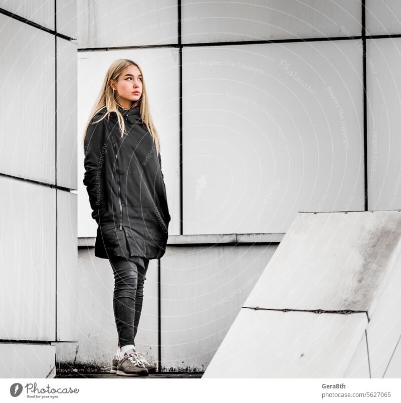 young girl with blond hair and black clothes against a gray building adult architecture autumn beautiful beauty blonde city dreamy erase face fashion female