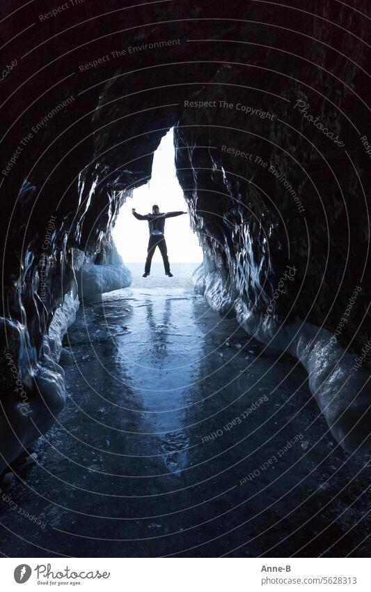 man jumping in front of the entrance to a beautiful ice cave from which the photo was taken Ice icily Cave Blue Human being Baikal Natural phenomenon Winter