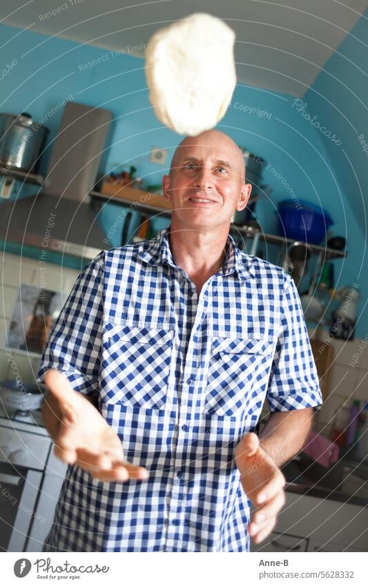 a cheerful man in a plaid shirt throws a pizza dough into the air in the kitchen Bakery Husband Household Househusband yeast cake yeast dough Toss yeast dough