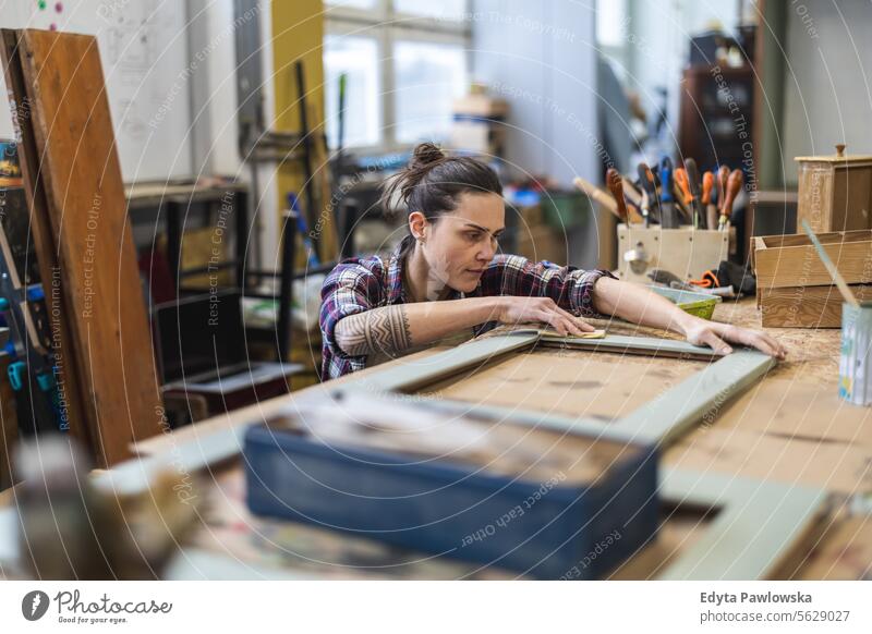 Portrait of young female carpenter working in her workshop Furniture Carpenter Restoring Carpentry wood Chair building Manufacturing Craft Renovation Repairing