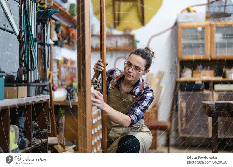 Portrait of young female carpenter working in her workshop Furniture Carpenter Restoring Carpentry wood Chair building Manufacturing Craft Renovation Repairing