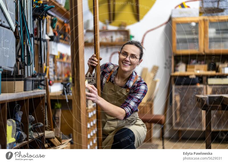 Portrait of young female carpenter working in her workshop Furniture Carpenter Restoring Carpentry wood Chair building Manufacturing Craft Renovation Repairing