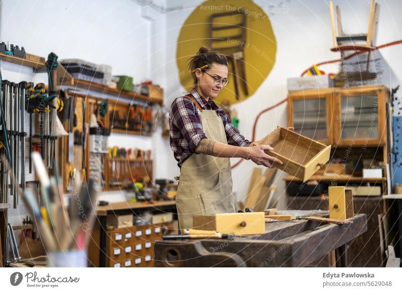 Portrait of young female carpenter working in her workshop Furniture Carpenter Restoring Carpentry wood Chair building Manufacturing Craft Renovation Repairing