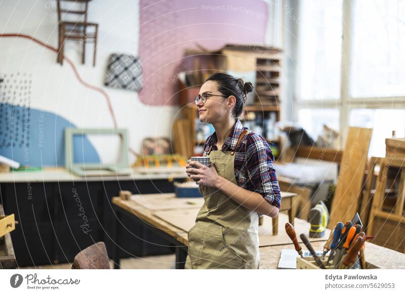 Portrait of a young female carpenter holding a cup of coffee in her workshop Furniture Carpenter Restoring Carpentry wood Chair building Manufacturing Craft