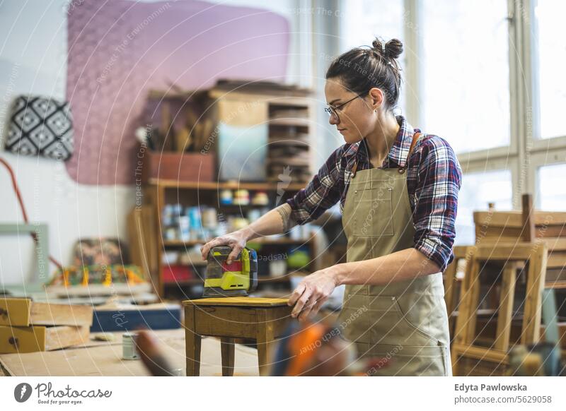 Portrait of young female carpenter working in her workshop Furniture Carpenter Restoring Carpentry wood Chair building Manufacturing Craft Renovation Repairing