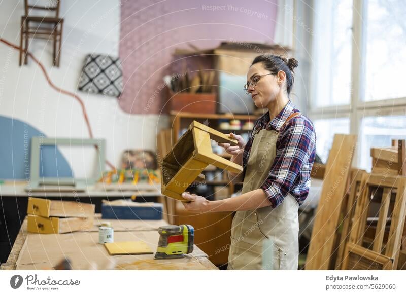 Portrait of young female carpenter working in her workshop Furniture Carpenter Restoring Carpentry wood Chair building Manufacturing Craft Renovation Repairing