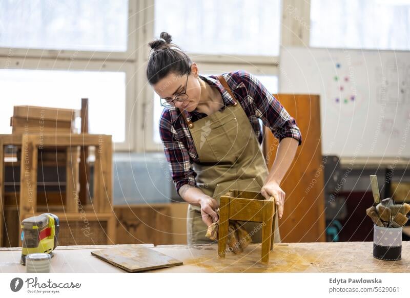 Portrait of young female carpenter working in her workshop Furniture Carpenter Restoring Carpentry wood Chair building Manufacturing Craft Renovation Repairing