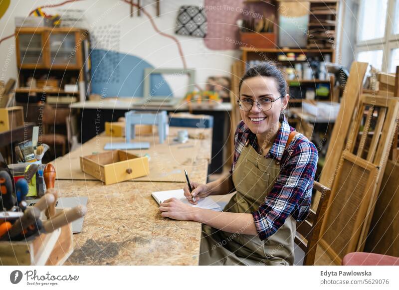 Portrait of young female carpenter working in her workshop Furniture Carpenter Restoring Carpentry wood Chair building Manufacturing Craft Renovation Repairing