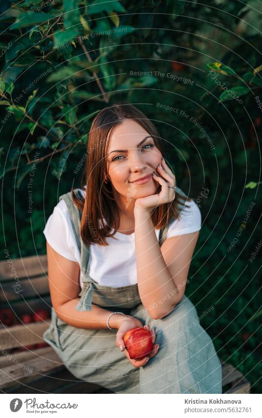 Woman gardener with red juicy apple from tree in own home countryside orchard adult agriculture apples autumn beautiful branch caucasian choosing customer diet