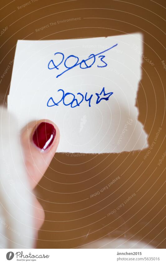 a piece of paper with the dates 2023 and 2024 is held by a finger with a red painted nail New Year's Eve Piece of paper Fingers Fingernail Varnished Nail polish