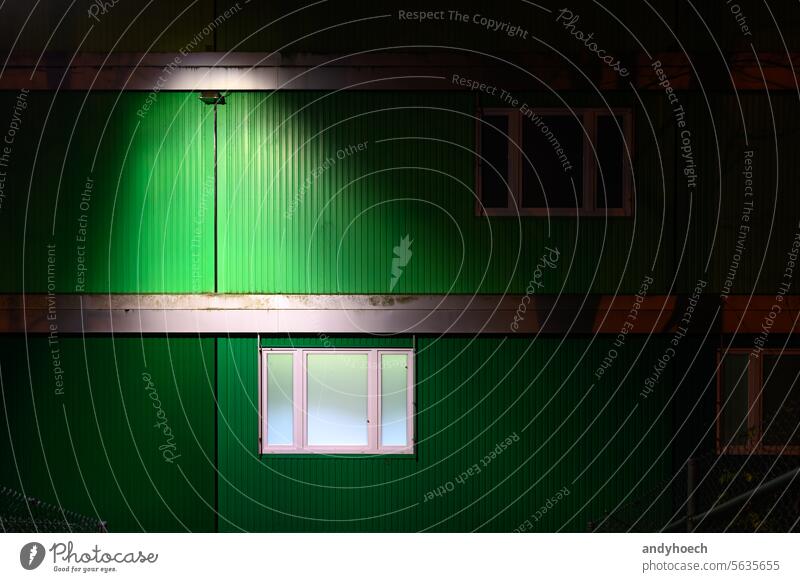 A green container home at night with an illuminated window accommodation apartment block architecture asylum blocks box building camp capacity construction