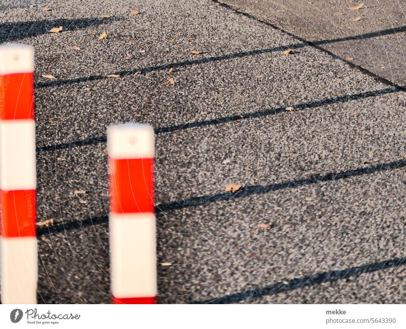 Long shadows behind the bollards Bollard piers Red White stop Border Boundary Barrier Street Fence Protection Safety Asphalt Bans cordon Reddish white