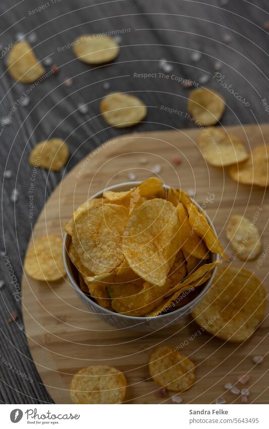 A bowl of potato chips stands on a wooden board Fast food Food Nutrition Eating Snack Unhealthy Appetite Delicious Fat Potatoes Close-up Colour photo