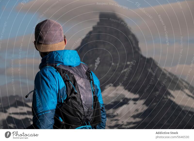 Hiker gazing at mountain peak surrounded by clouds hiker jacket adventure nature contemplation travel outdoor hiking explorer scenery majestic wilderness trail