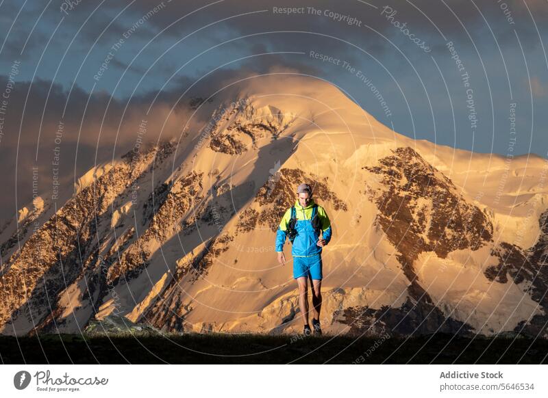 Adventurer hiking in mountain terrain at sunset adventurer snow backpack trek majestic outdoors nature wilderness travel explorer journey sport fitness activity