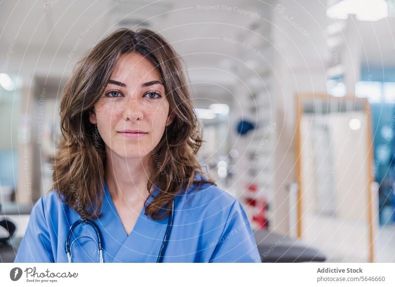 Happy young woman doctor in uniform sitting at table in hospital portrait smile professional stethoscope work health care job female happy therapist medical