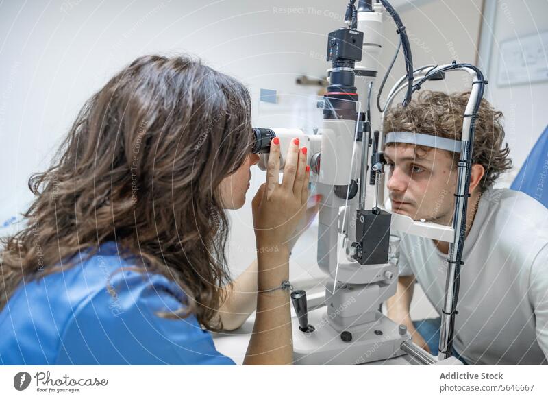 Young woman doctor testing eye of unrecognizable man at clinic in lights patient uniform stethoscope check up split lamp biomicroscope hospital female young sit