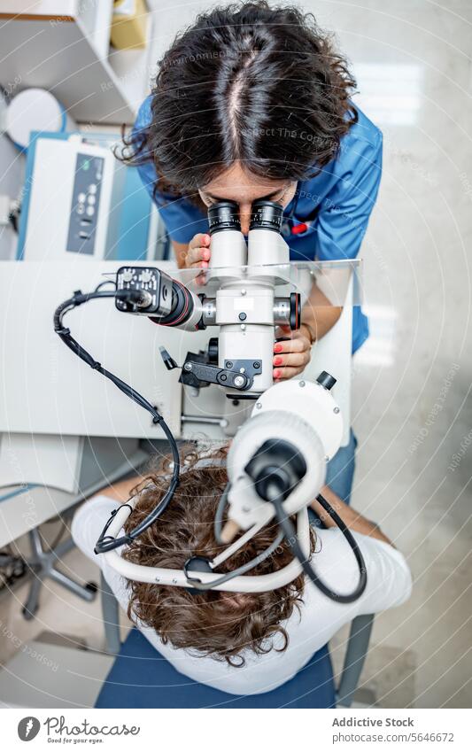 Young woman doctor testing eye of unrecognizable man at clinic in lights patient uniform stethoscope check up split lamp biomicroscope hospital female young sit