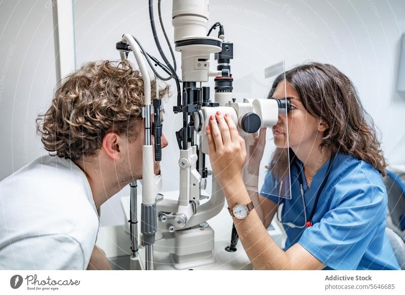 Young woman doctor testing eye of unrecognizable man at clinic in lights patient uniform stethoscope check up split lamp biomicroscope hospital female young sit