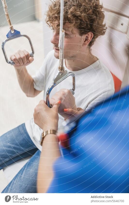 Young man sitting in hospital and holding hanging holders patient clinic curly hair interior illness equipment comfort male young health care inside guy therapy