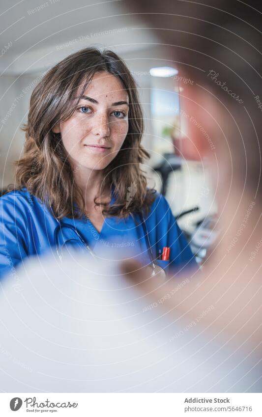 Smiling young female doctor looking at camera while standing in hospital woman smile uniform medical corridor clinic specialist nurse health care professional