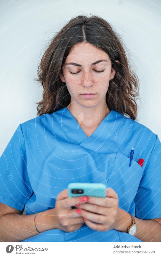 Young female nurse browsing smartphone while sitting on bench woman hospital using uniform medicine relax gadget device mobile medical connection cellphone