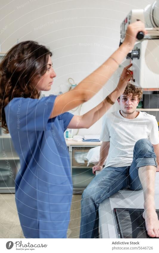 Young female technician adjusts X Ray machine for scanning patient sitting on bed in clinic woman nurse x ray hospital diagnosis health care medicine