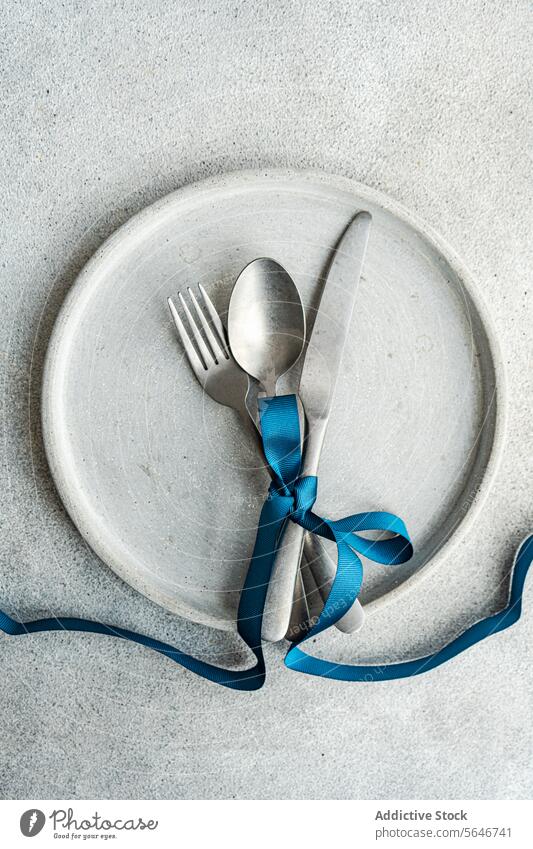 Top view of Minimalist Easter Table Decor minimalist table decor blue ribbon concrete backdrop simplicity texture stylish rough texture ribbon-tied cutlery