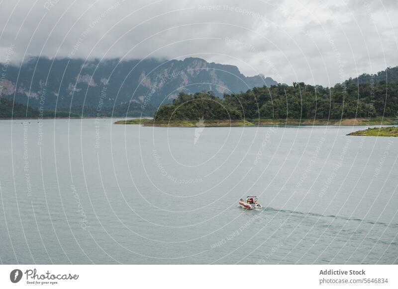 Boat floating on calm sea near mountain under cloudy sky in Thailand boat water nature picturesque ridge transport ripple vessel trip ocean shore weather