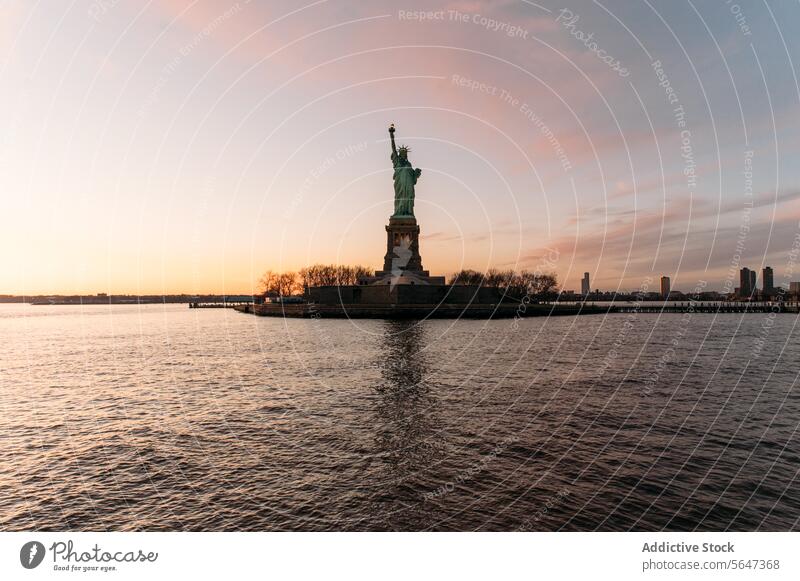 Statue of Liberty on shore under sundown sky statue statue of liberty monument landmark america usa united states river new york sunset ripple district city