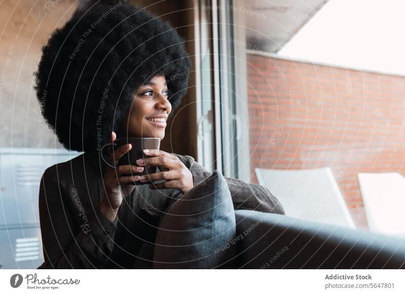 Cheerful black woman with cup of coffee hot drink beverage afro window smile leisure refreshment hairstyle feminine appearance happy charming brunette