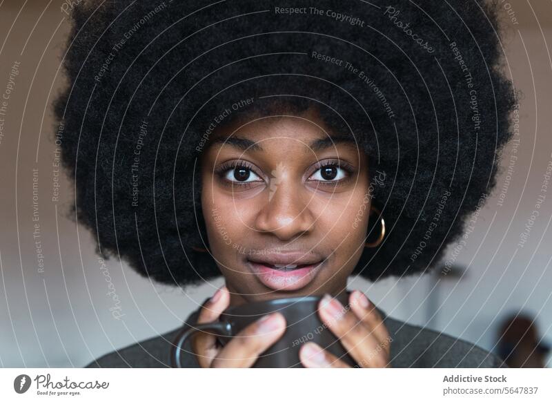 Positive black woman with hot beverage cup hot drink coffee afro feminine hairstyle dreamy smile appearance happy charming brunette attractive female cheerful